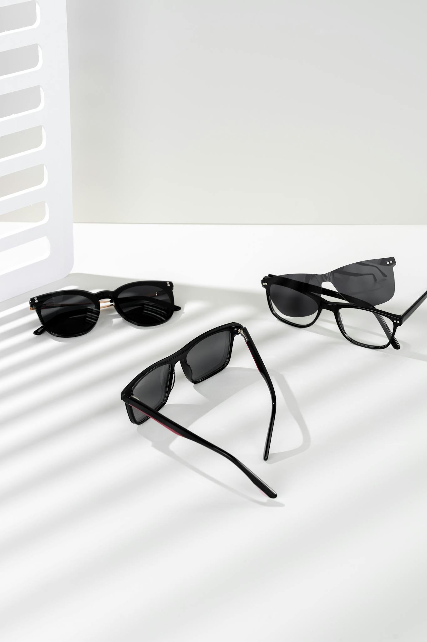 Array of stylish sunglasses on a white background with artistic shadows.