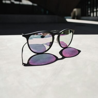 Modern sunglasses casting a shadow with colorful reflections in an urban setting.