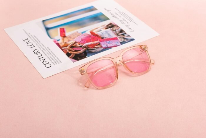 Pink sunglasses on a magazine page with a soft pastel background, capturing a chic and modern vibe.