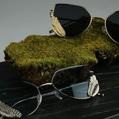 Stylish gold and silver sunglasses resting on a green moss background.