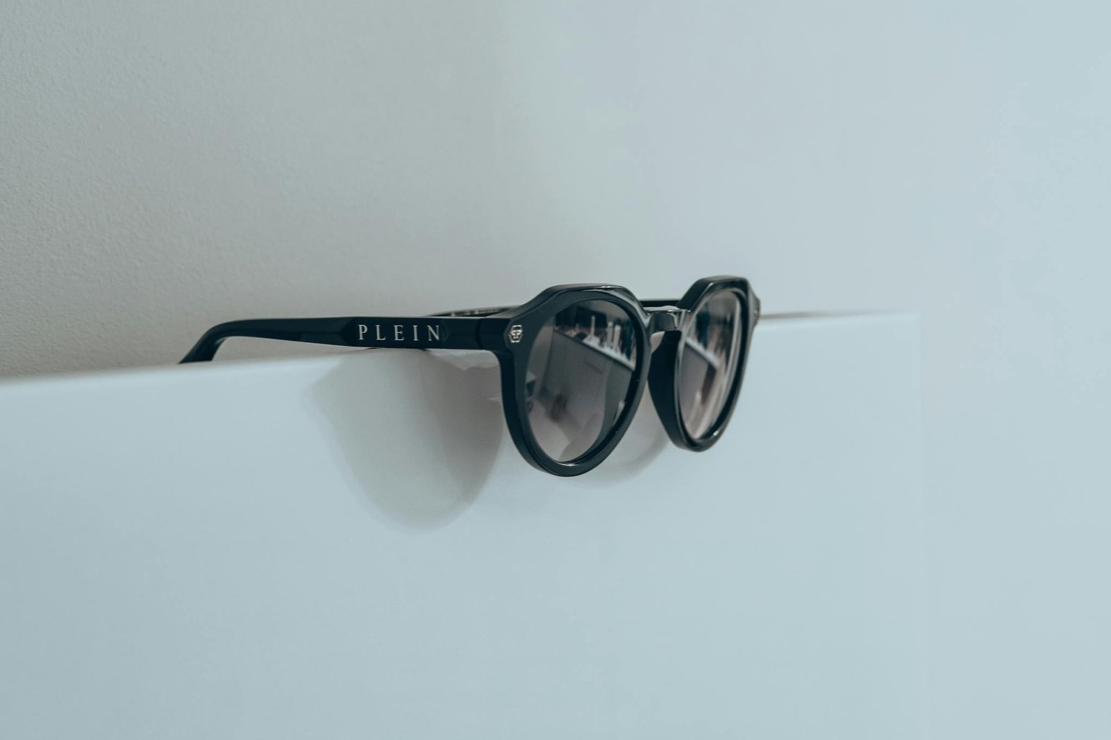 Stylish sunglasses with black frames resting on a white surface showcasing minimalist design.